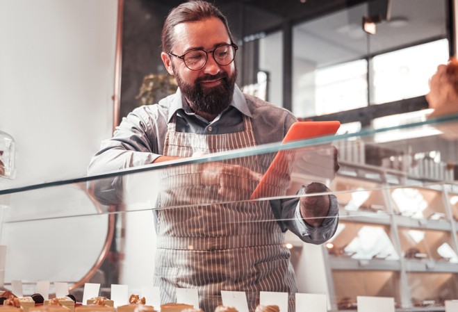 Boulanger regardant sur son smartphone devant son comptoir