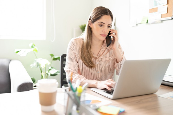 femme au téléphone qui regarde son ordinateur