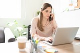 femme au téléphone qui regarde son ordinateur