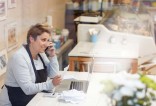 Commerçante entrain de passer un appel téléphonique à la caisse de son magasin