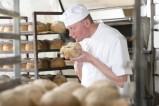 Un boulanger entrain de sentir un pain artisanal qu'il vient de préparer.
