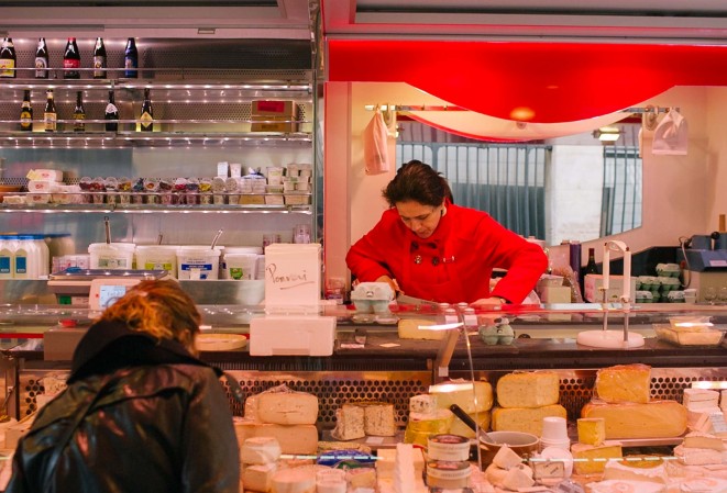 Madame Pommier fromagère au marché Aligre de Paris XIIe entrain de couper une tranche de fromage pour une cliente