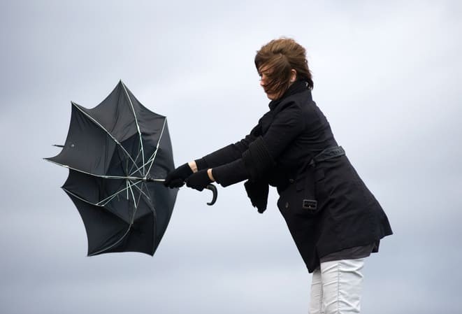 Femme tenant un parapluie noir qui s'est retourné