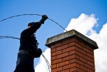Artisan entrain de ramoner une cheminée sur le toit d'une maison