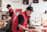Les risques de TMS du Maître Artisan Boucher de la Boucherie Delmas portant des barquettes de viande