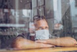 homme portant un masque qui regarde à travers une vitre