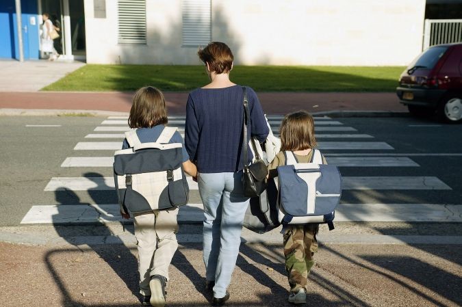 Maman tient la main de ses deux enfants pour traverser un passage piéton