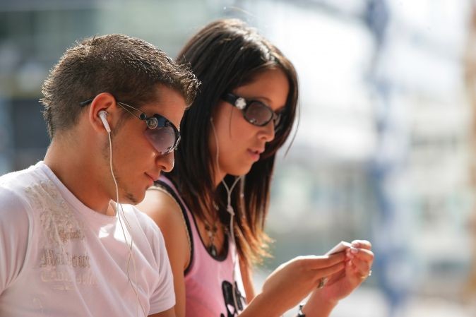 Homme et femme entrain d'écouter de la musique avec des écouteurs blancs