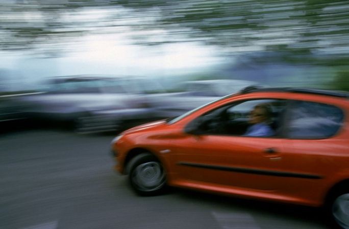 Peugeot 206 orange entrain de rouler sur un parking