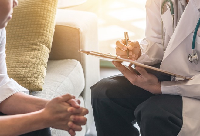 Médecin en consultation en train d'écrire sur un bloc avec un stylo