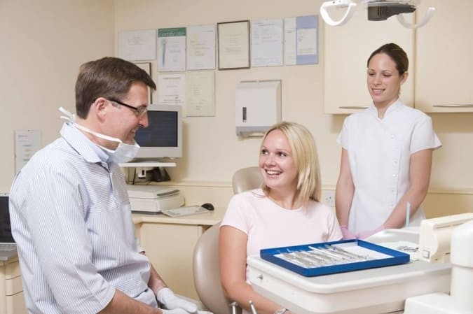 Chirurgien dentiste et son assistante dentaire en consultation avec une patiente 
