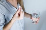 Femme entrain de prendre un comprimé avec un verre d'eau