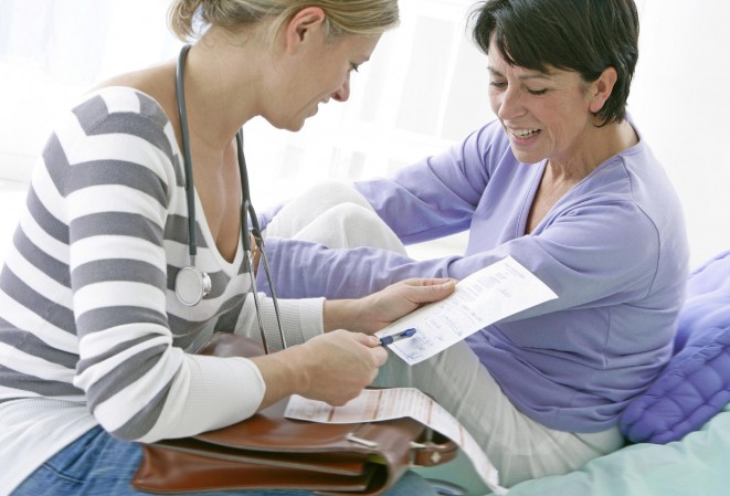 Médecin en consultation avec une patiente entrain de regarder ensemble une ordonnance et une feuille de soins.