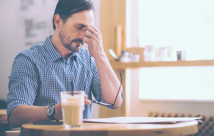 Homme assis à une table qui a mal à la tête