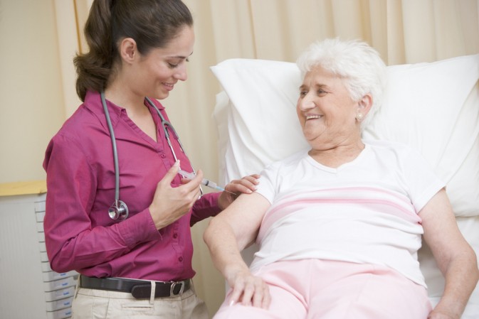 Femme infirmière vaccinant une dame âgée allongée dans un lit d'hôpital 