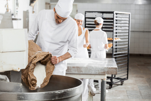 Boulanger versant de la farine dans un pétrin