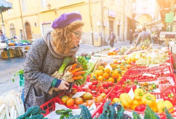 Femme entrain d'acheter des fruits et des légumes à un primeur