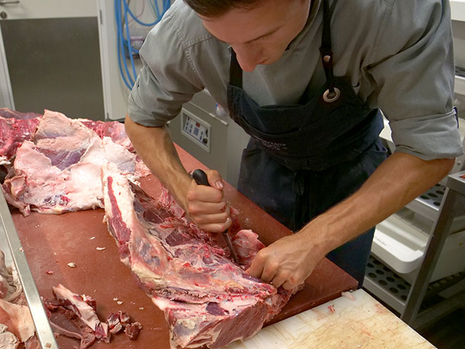 Apprenti boucher entrain de découper une carcasse