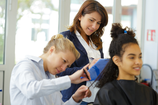 Élève en BM coiffure entrain de couper les cheveux d'une cliente