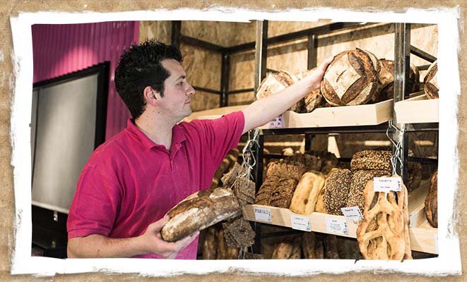 Boulanger entrain de déposer du pain dans ses présentoirs