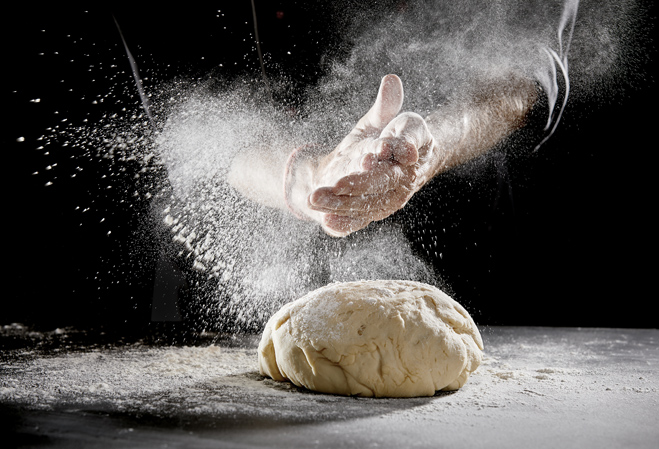 Boulanger se frottant les mains pour enlever de la farine pendant la préparation d'une pâte à pain
