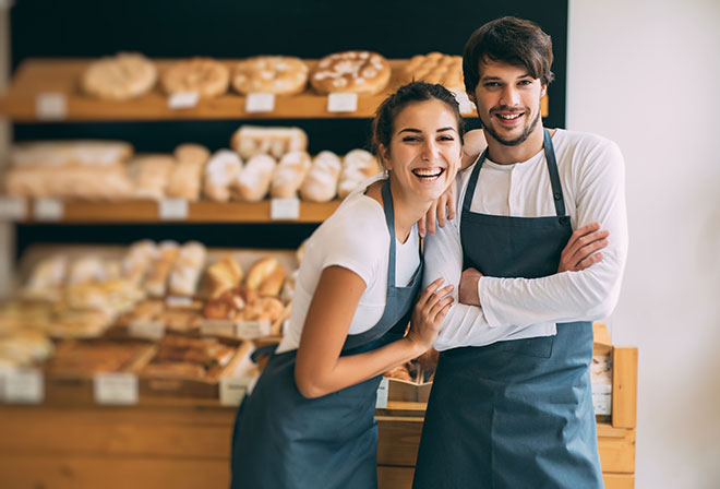 Boulanger et boulangère dans leur boutique entrain de sourire