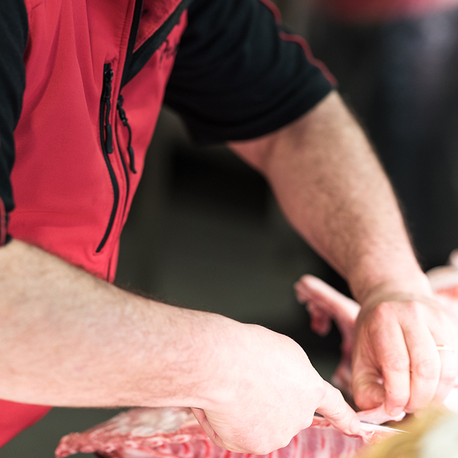 Gros plan sur les mains d'un boucher entrain de découper une pièce