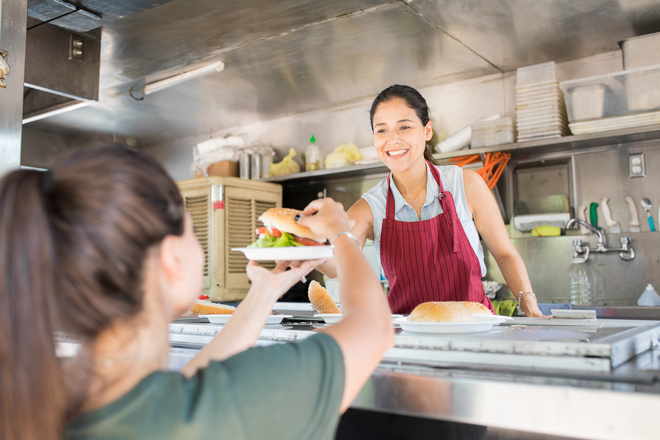 Commerçante sert un burger à une cliente