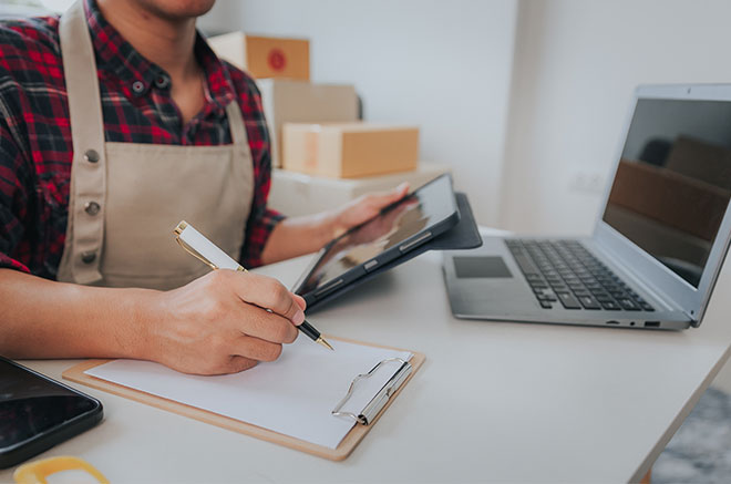 Commerçant entrain de remplir des papiers devant son ordinateur