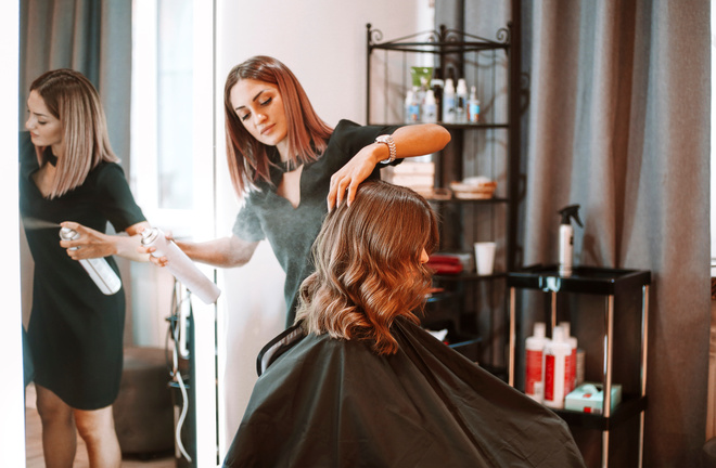 Coiffeuse applique de la laque sur les cheveux d'une cliente