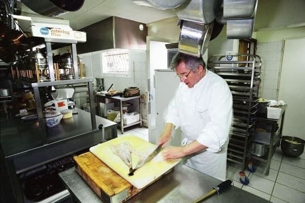 Cuisinier entrain de couper un poisson