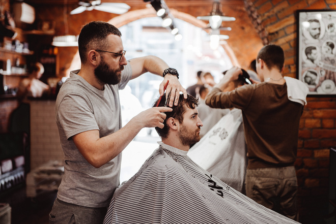 Coiffeur pour homme entrain de couper les cheveux d'un client