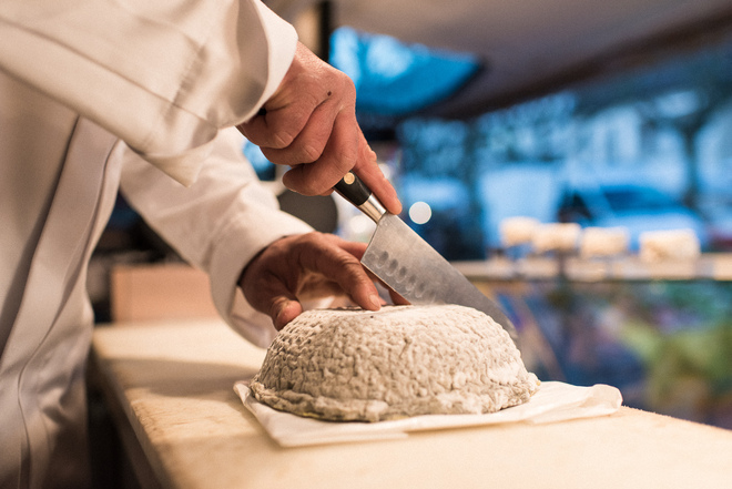 Découpe d'un fromage par un fromager