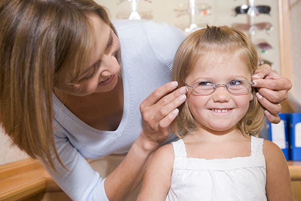 Jeune fille entrain d'essayer des lunettes de vue avec sa maman