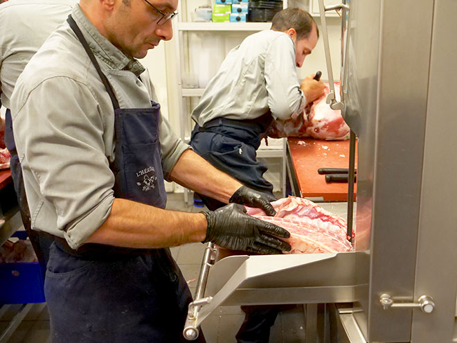 Boucher en formation adulte entrain de découper une carcasse à la scie