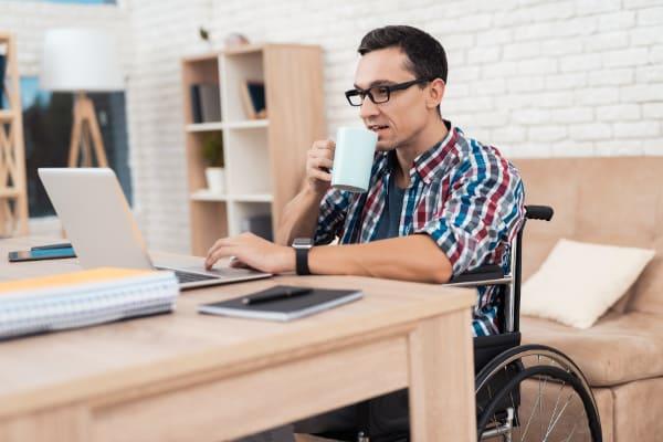 Homme en fauteuil roulant entrain de travailler sur son ordinateur portable