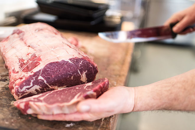 Découpe de pièces de boeuf par le boucher