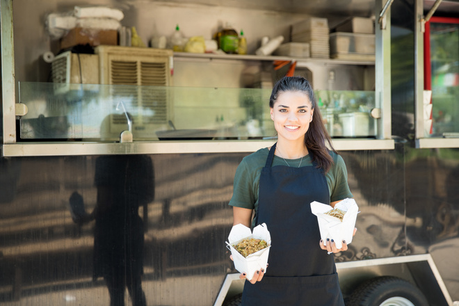 Commerçante devant son food truck avec deux portions de nourriture