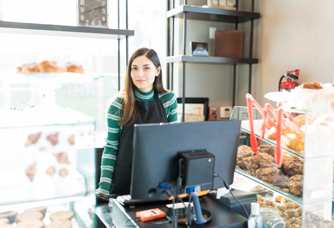 Une commerçante vendeuse devant son comptoir et son ordinateur PC