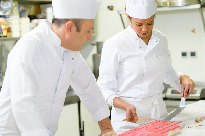 Professeur surveille la préparation de pâtisseries par une élève