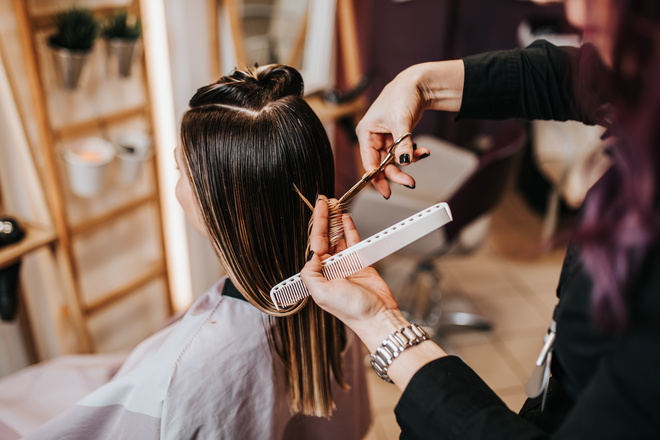 Gros plan sur une coiffeuse entrain de couper les cheveux d'une cliente