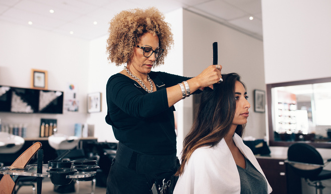 Coiffeuse entrain de couper les cheveux d'une cliente