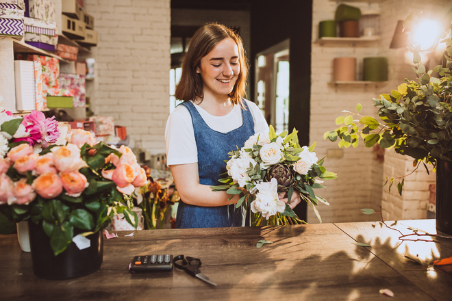 Apprentie fleuriste entrain de réaliser un bouquet au comptoir