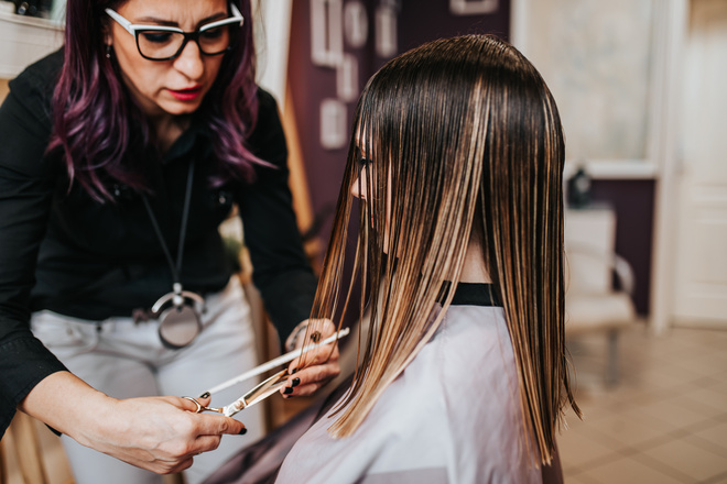 Coiffeuse coupe les cheveux longs d'une cliente