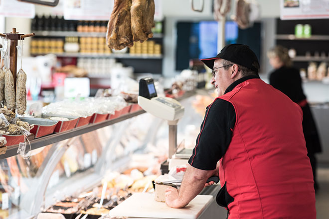 Découpe et vente de pâté à des clients en boucherie