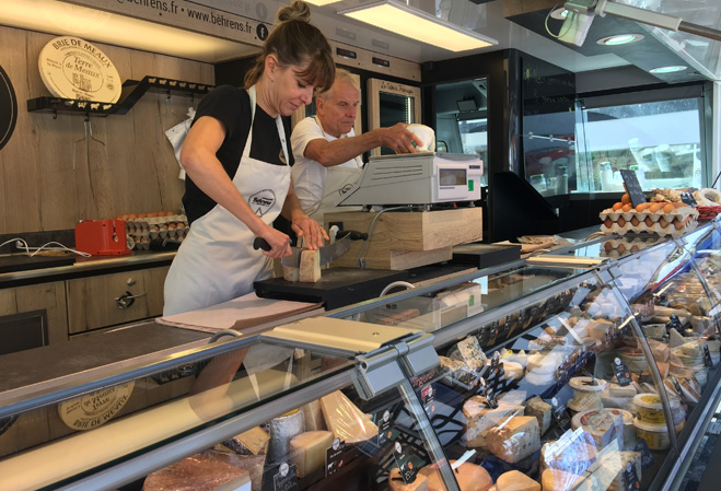 Stella Renaudin dans son camion magasin avec son père coupant du fromage pour des clients
