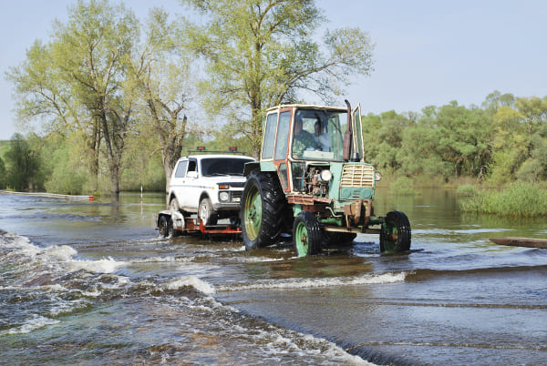 Vehicule remorqué par un tracteur sur une route complètement inondée