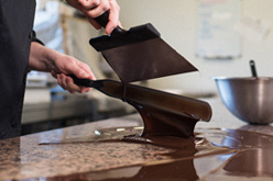 Chocolatier déversant du chocolat sur un plan de travail