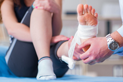 Médecin en train de faire un bandage du pied à une femme