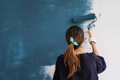 Femme peintre en bâtiment peignant un mur en bleu